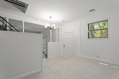 Spare room featuring a chandelier, ornamental molding, plenty of natural light, and light tile patterned floors