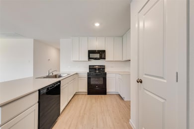 Kitchen with sink, white cabinetry, light wood-typ