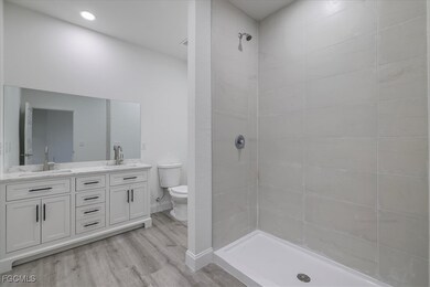 Full bath with double vanity, tiled shower, and wo