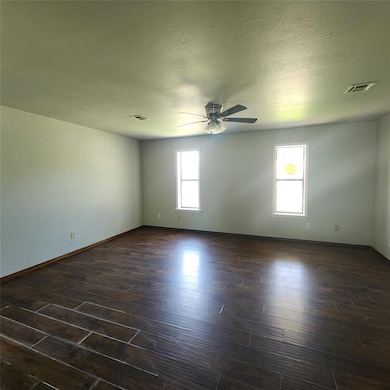 Living room featuring ceiling fan, dark wood finished floors, and a textured ceiling