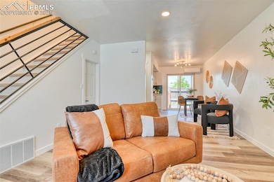 Living area with a wall mounted air conditioner, light wood-style floors, baseboards, and recessed lighting