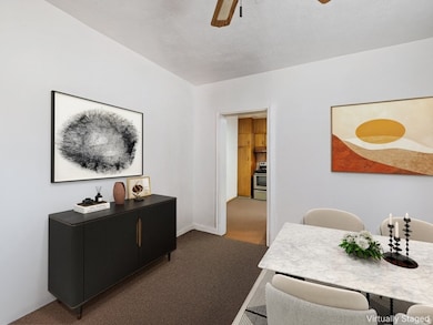Carpeted dining area with a ceiling fan and a textured ceiling