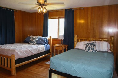 Bedroom with wood walls, a ceiling fan, and wood finished floors