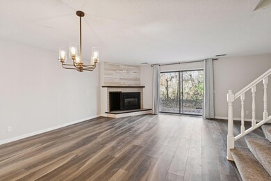 Bright and airy living space with wide-plank flooring, a stylish chandelier, and sliding glass doors that fill the room with natural light.