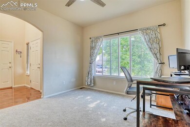 Office featuring arched walkways, carpet floors, and a ceiling fan