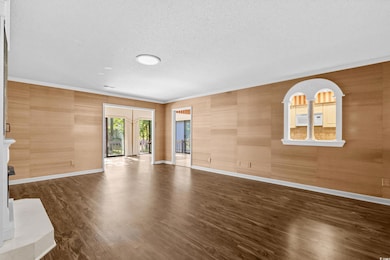 Unfurnished living room with a textured ceiling, dark wood-style floors, and a fireplace with raised hearth