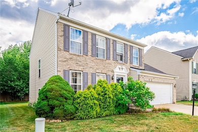 Colonial house featuring a garage, concrete driveway, a front lawn, and brick siding