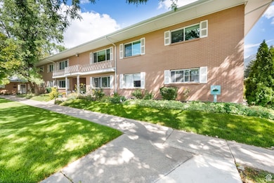 View of front of home with a front yard, brick siding, and a balcony