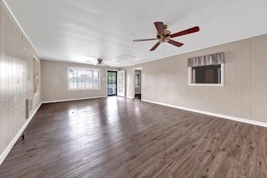 Spare room with a ceiling fan, wood finished floors, attic access, and wood walls
