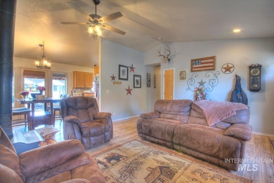 Living area with vaulted ceiling, wood finished floors, ceiling fan, and a chandelier