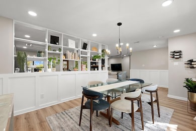 Dining space with a wainscoted wall, light wood-type flooring, recessed lighting, and a chandelier
