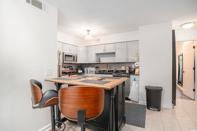 Kitchen featuring tasteful backsplash, light tile patterned floors, appliances with stainless steel finishes, a textured ceiling, and dark countertops