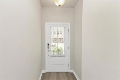 Doorway with baseboards and wood finished floors