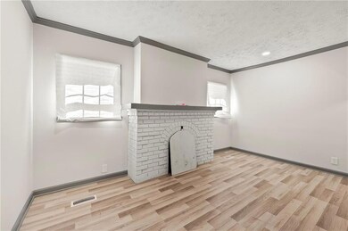 Unfurnished living room featuring crown molding, a fireplace, a textured ceiling, wood finished floors, and baseboards