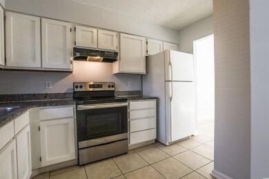 Kitchen with electric range, white cabinetry, whit