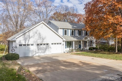 Traditional-style home with concrete driveway, roof with shingles, a garage, covered porch, and a front yard