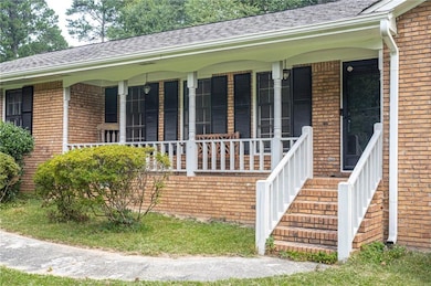 Entrance to property with a porch, brick siding, and roof with shingles