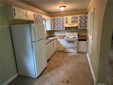 Kitchen with white appliances, under cabinet range hood, a textured ceiling, crown molding, and white cabinets
