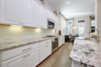 This sleek kitchen showcases white cabinetry, gran