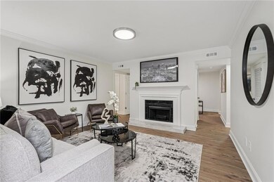 Living area with crown molding, wood finished floors, and a tiled fireplace