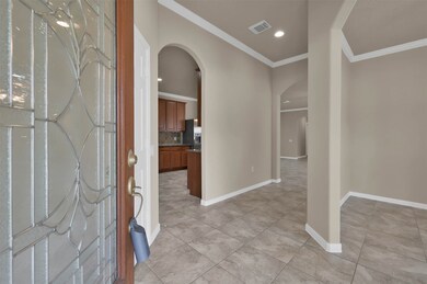 Beautiful foyer filled with crown molding, curved archways, and tile throughout main living area.