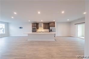 Unfurnished living room with baseboards, light woo
