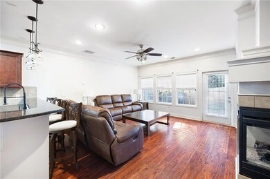 Living room featuring ornamental molding, a tiled fireplace, dark wood-type flooring, recessed lighting, and ceiling fan