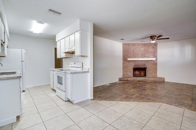Kitchen featuring white cabinetry, white appliances, a ceiling fan, a textured ceiling, and a fireplace