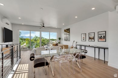 Dining space with light wood finished floors, a ceiling fan, recessed lighting, and a wall mounted air conditioner