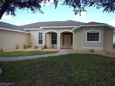 Ranch-style house with a front yard and stucco sid