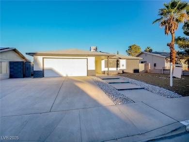 Single story home with concrete driveway, a gate, brick siding, and an attached garage