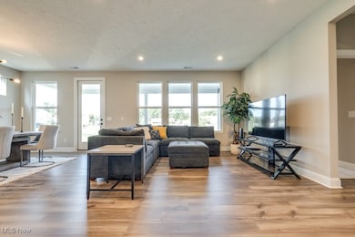 Living room with light wood-type flooring, recessed lighting, and a textured ceiling