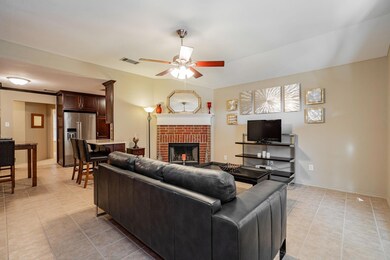 Tiled living room with a fireplace and ceiling fan