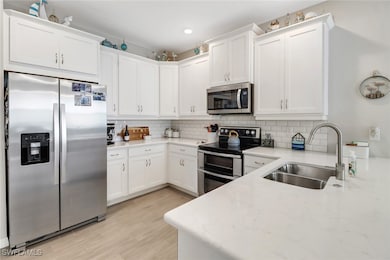 Kitchen featuring tasteful backsplash, white cabinetry, sink, and stainless steel appliances
