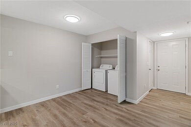 Entry to the home with light wood-type flooring and separate washer and dryer in the laundry closet