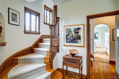 Beautiful foyer with curved staircase, original lead casement windows, hardwood floors and archways