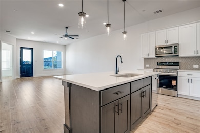 Kitchen featuring open floor plan, appliances with stainless steel finishes, white cabinetry, tasteful backsplash, and recessed lighting