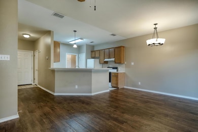 Kitchen featuring white appliances, brown cabinets, dark wood-style floors, and light countertops