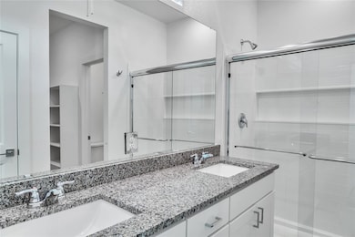Bathroom featuring a sink, a shower stall, and dou