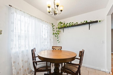 Dining room with light tile patterned floors, a textured ceiling, and a chandelier