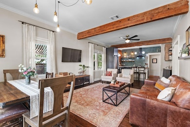 Living room featuring ornamental molding, beam ceiling, dark wood-style floors, and a ceiling fan