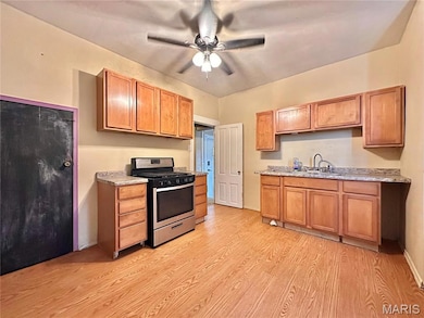 Kitchen featuring stainless steel gas range, light wood finished floors, light countertops, and a ceiling fan