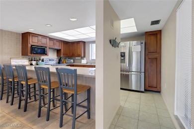 Kitchen with a kitchen breakfast bar, light tile patterned floors, light countertops, visible vents, and stainless steel appliances