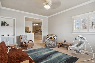 Living area featuring ornamental molding, built in shelves, a chandelier, and light carpet
