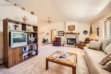 Living area with carpet floors, a fireplace, ceiling fan, and lofted ceiling