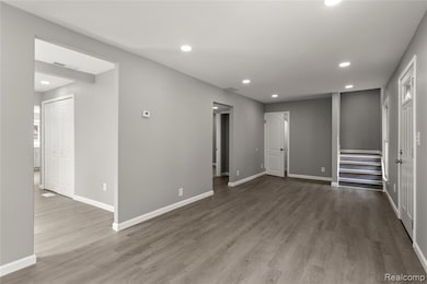 Empty room with recessed lighting, light wood-style floors, and stairs