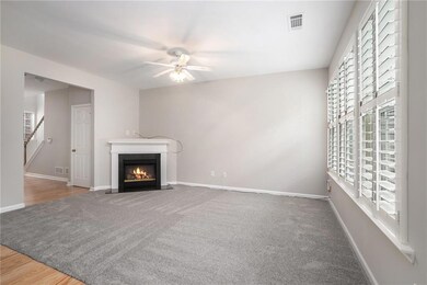 Unfurnished living room with a ceiling fan, plenty of natural light, a glass covered fireplace, and carpet floors