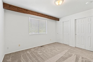 Primary bedroom featuring two closets, NEW carpet & pad, and beamed ceiling