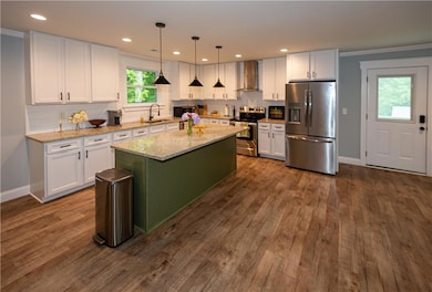 Kitchen featuring baseboards, wall chimney range h