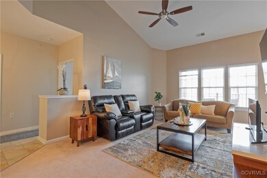 Carpeted living room with ceiling fan and high vau